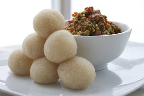 Four balls of swallow on separate plates beside bowls of vegetable soup, ready to be compared