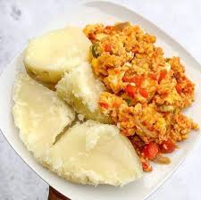Slices of boiled white yam on a plate beside a fried egg