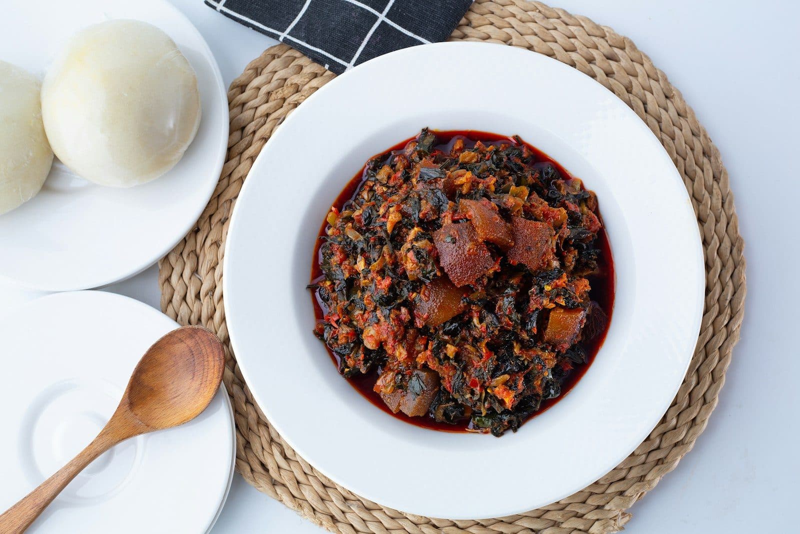 Two balls of white swallow beside a plate of vegetable soup with cow skin